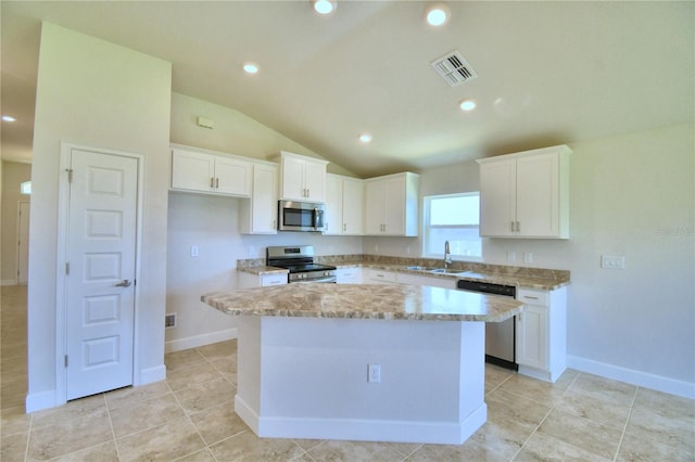 kitchen with stainless steel appliances, a kitchen island, white cabinetry, and lofted ceiling