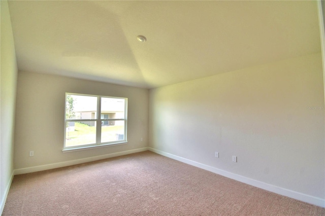 spare room featuring light colored carpet and lofted ceiling