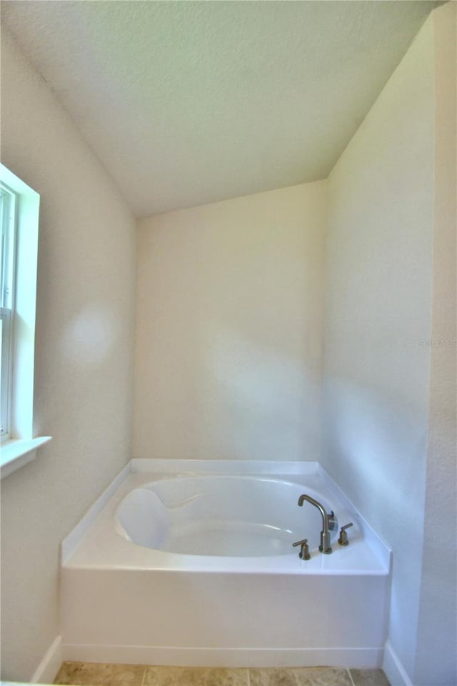 bathroom featuring tile patterned flooring, a bath, and a textured ceiling