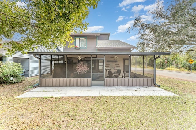 view of front of property with a front lawn, roof with shingles, and a sunroom