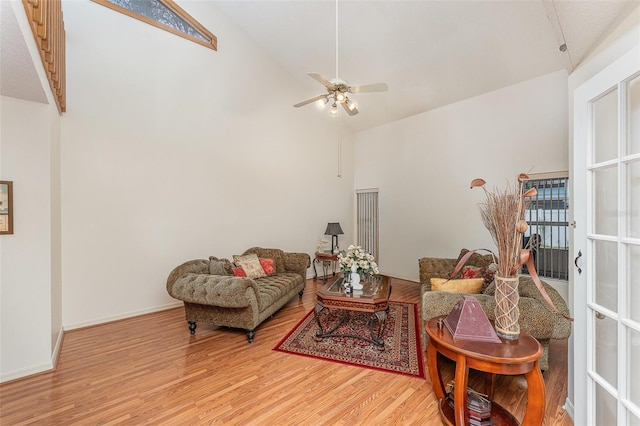 living room with high vaulted ceiling, ceiling fan, baseboards, and wood finished floors