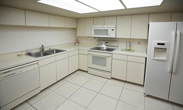 kitchen featuring white appliances, light countertops, a sink, and light tile patterned flooring