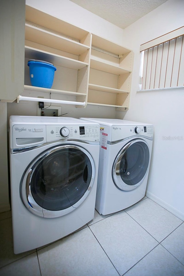 laundry room with light tile patterned flooring, a textured ceiling, separate washer and dryer, laundry area, and baseboards