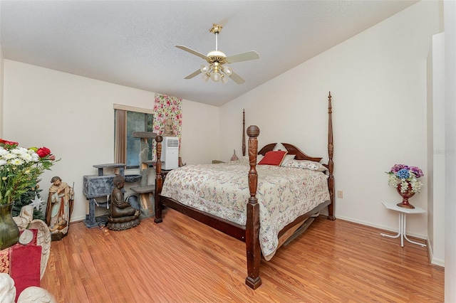 bedroom featuring lofted ceiling, ceiling fan, a textured ceiling, baseboards, and light wood-type flooring