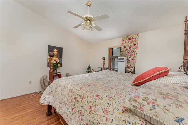 bedroom with a textured ceiling, a ceiling fan, baseboards, vaulted ceiling, and light wood finished floors