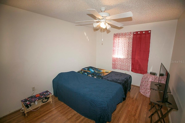 bedroom with a textured ceiling, wood finished floors, and a ceiling fan