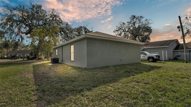 property exterior at dusk with a yard and central air condition unit