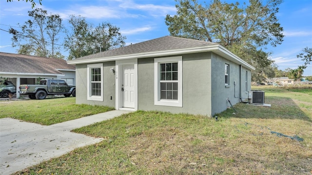 bungalow-style home featuring cooling unit and a front lawn