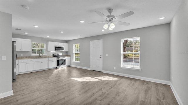 kitchen with appliances with stainless steel finishes, light hardwood / wood-style floors, sink, and white cabinets