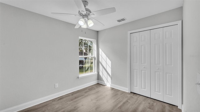 unfurnished bedroom featuring ceiling fan, light hardwood / wood-style floors, and a closet