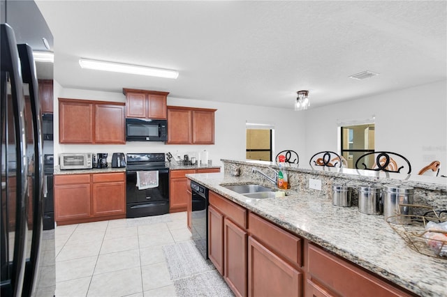 kitchen with light stone counters, a textured ceiling, sink, black appliances, and light tile patterned floors