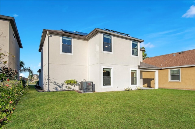 rear view of property featuring central AC, a yard, and solar panels