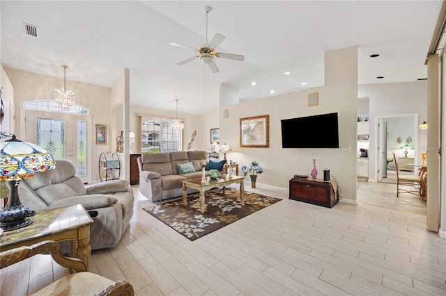 living room with ceiling fan with notable chandelier and high vaulted ceiling