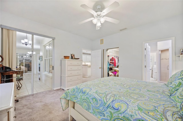 bedroom featuring a spacious closet, ensuite bath, a closet, light colored carpet, and ceiling fan with notable chandelier