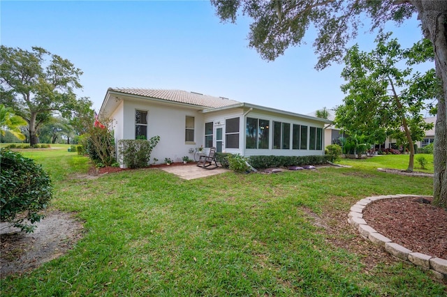 rear view of property with a patio area, a lawn, and a sunroom