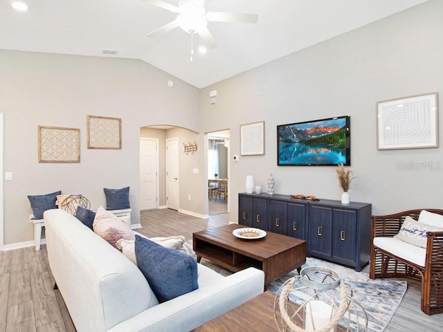 living room with ceiling fan, high vaulted ceiling, and light hardwood / wood-style flooring