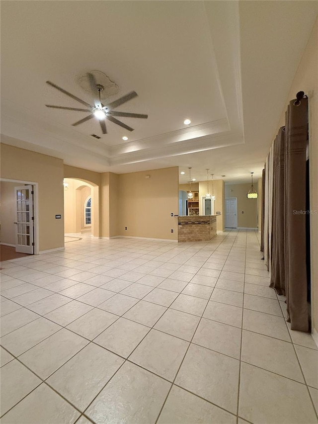 tiled spare room with ceiling fan and a tray ceiling