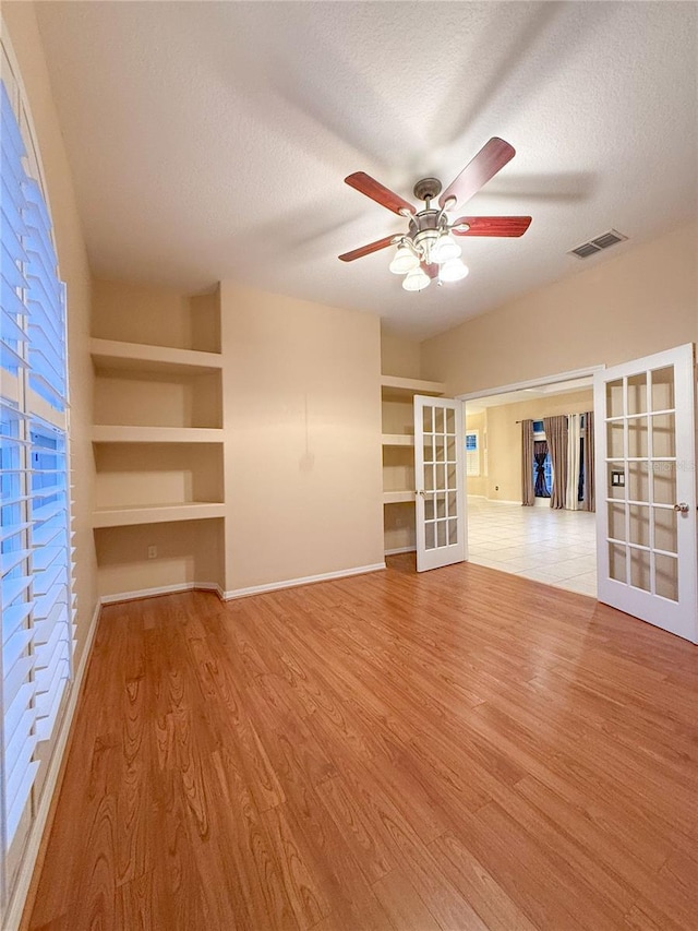 unfurnished living room featuring french doors, a textured ceiling, light hardwood / wood-style flooring, and ceiling fan