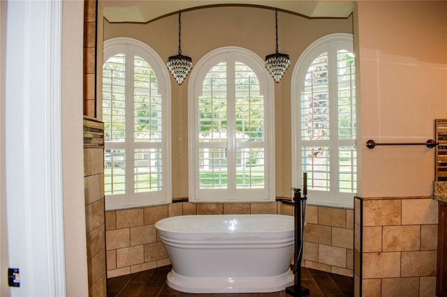 bathroom with tile patterned floors, a bath, tile walls, and a chandelier