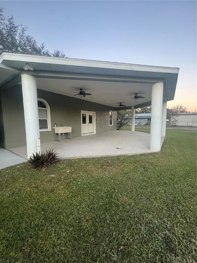 parking at dusk featuring a lawn and ceiling fan