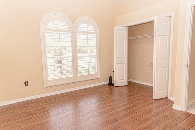 2638 E Knights Griffin Rd, Plant City, FL 33565 - unfurnished bedroom with wood finished floors, multiple windows, baseboards, and a closet