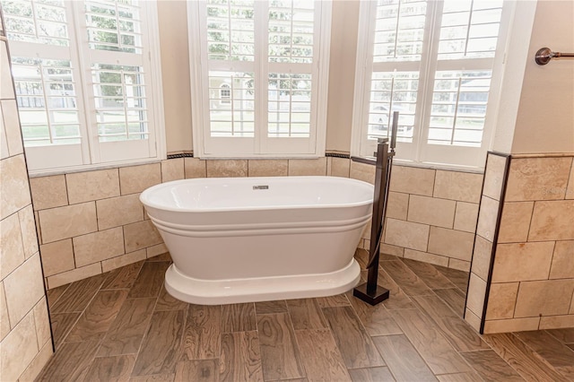 2638 E Knights Griffin Rd, Plant City, FL 33565 - bathroom with tile walls, a freestanding tub, a wainscoted wall, and wood finished floors