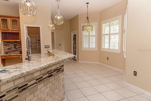 2638 E Knights Griffin Rd, Plant City, FL 33565 - kitchen with light tile patterned floors, pendant lighting, decorative backsplash, and light stone counters