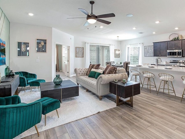 living room featuring ceiling fan, light hardwood / wood-style flooring, and sink