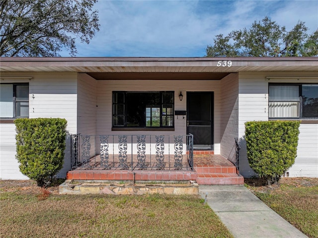 property entrance featuring covered porch and a lawn