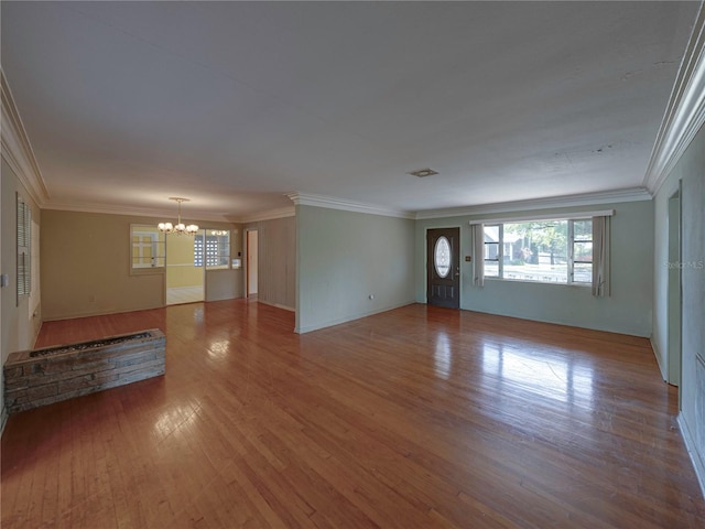 unfurnished living room with hardwood / wood-style floors, an inviting chandelier, and ornamental molding