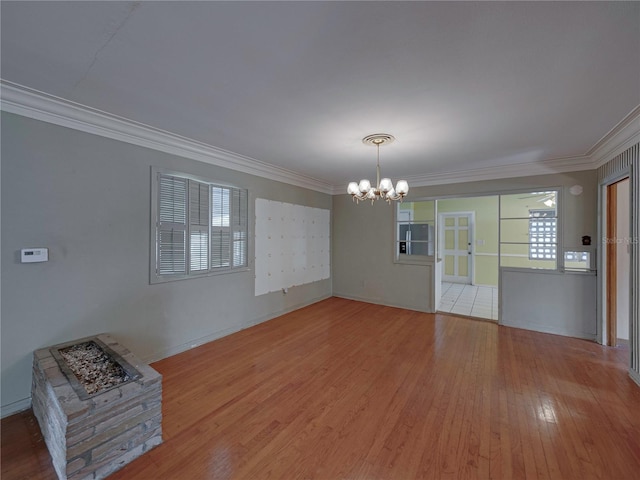 unfurnished room featuring hardwood / wood-style flooring, an inviting chandelier, and ornamental molding