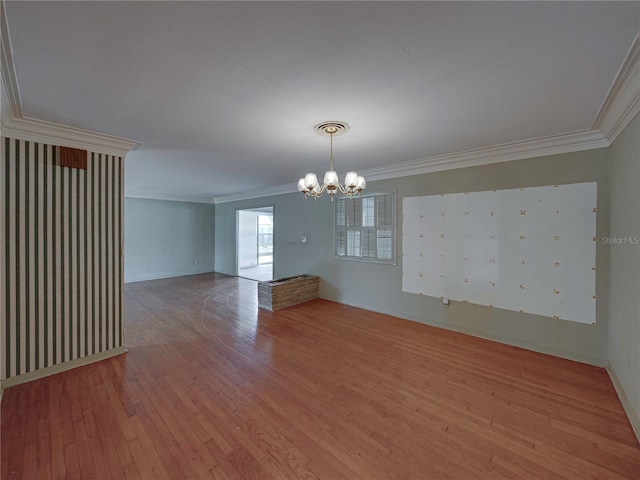 empty room featuring ornamental molding, wood-type flooring, and a notable chandelier