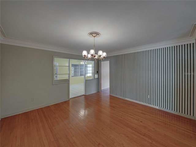 empty room featuring hardwood / wood-style floors, an inviting chandelier, and crown molding