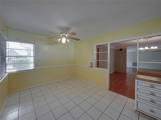 spare room with ceiling fan with notable chandelier and light hardwood / wood-style floors