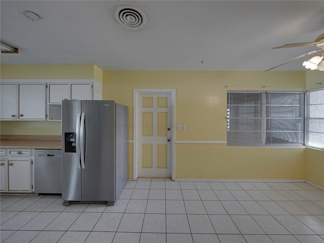 kitchen with stainless steel refrigerator with ice dispenser, ceiling fan, light tile patterned floors, dishwasher, and white cabinetry