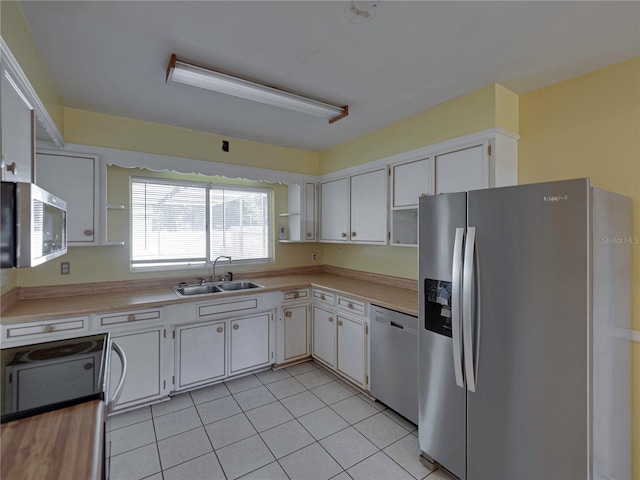 kitchen with light tile patterned flooring, sink, white cabinets, and stainless steel appliances