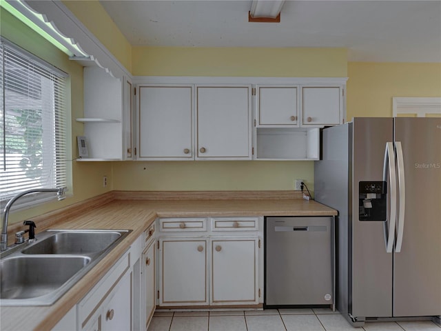 kitchen featuring white cabinets, appliances with stainless steel finishes, light tile patterned flooring, and sink