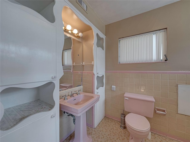 bathroom featuring tile patterned floors, toilet, and tile walls