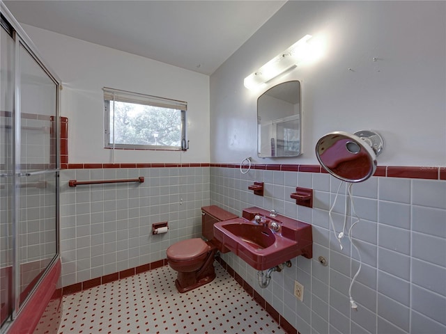 full bathroom featuring sink, tile patterned floors, combined bath / shower with glass door, toilet, and tile walls