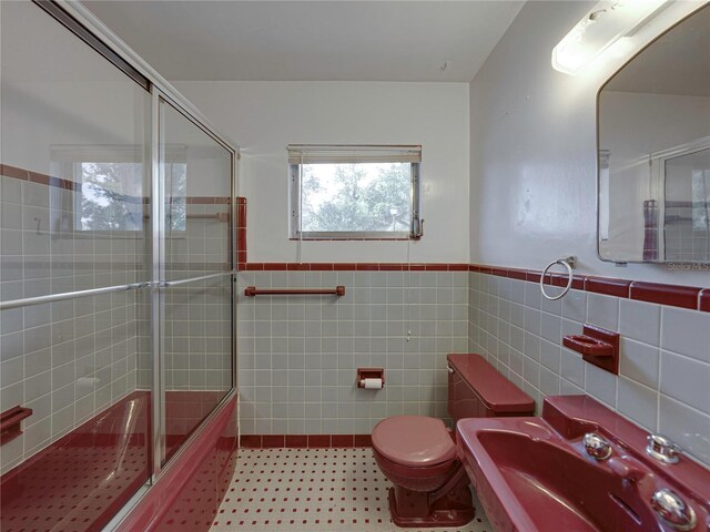 full bathroom with enclosed tub / shower combo, toilet, tile walls, and sink