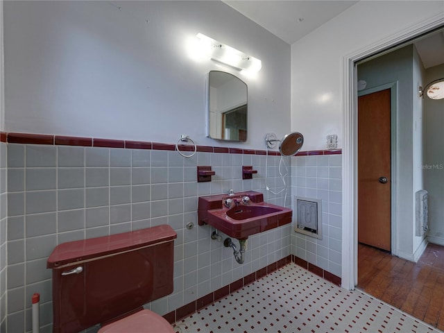 bathroom with tile patterned flooring, toilet, sink, and tile walls