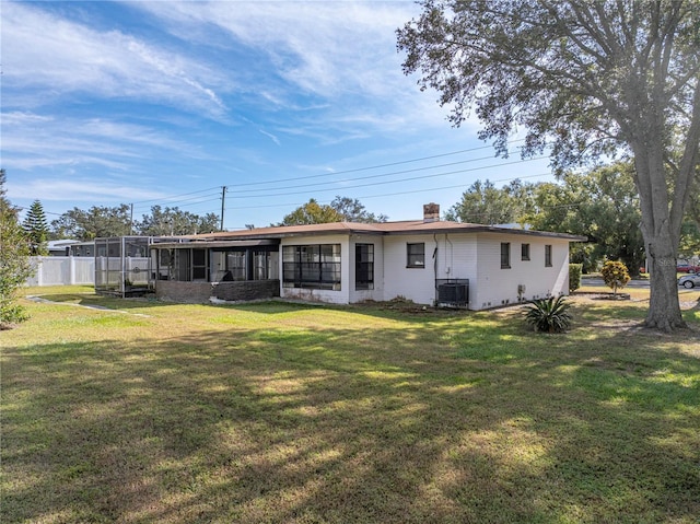 rear view of property featuring a sunroom, cooling unit, and a yard