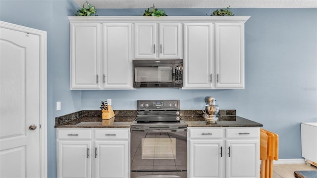 kitchen featuring dark stone counters, white cabinetry, light tile patterned floors, and black appliances