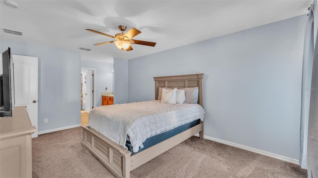 bedroom featuring light carpet, ensuite bathroom, and ceiling fan