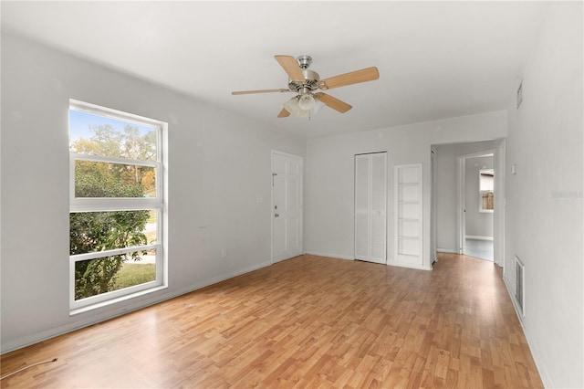 spare room featuring ceiling fan, a healthy amount of sunlight, and light hardwood / wood-style flooring