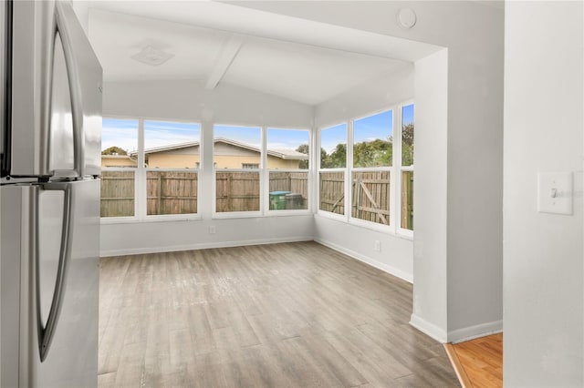 unfurnished sunroom featuring lofted ceiling with beams