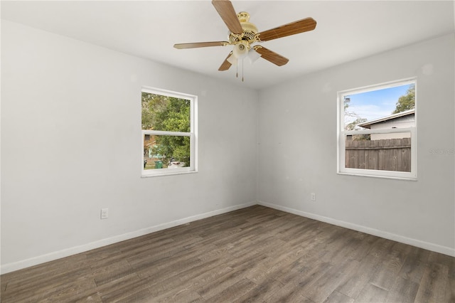 empty room featuring ceiling fan, a healthy amount of sunlight, and dark hardwood / wood-style flooring