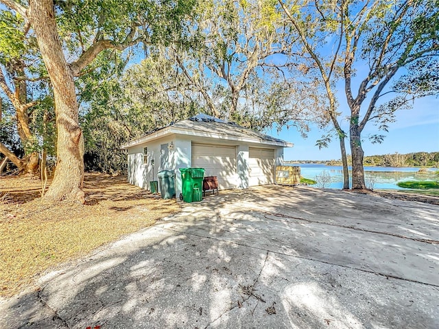 exterior space with a garage, a water view, and an outdoor structure