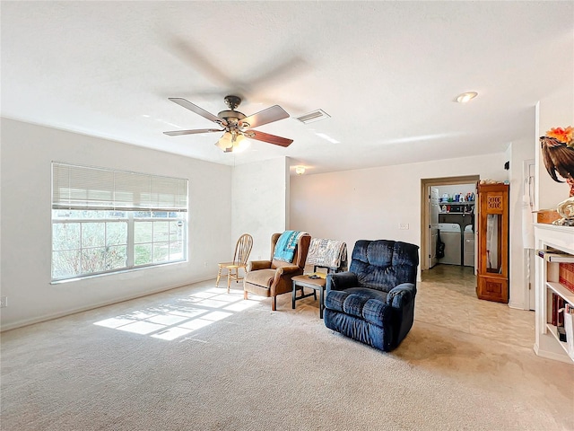 sitting room with a fireplace, ceiling fan, washer and dryer, and light colored carpet