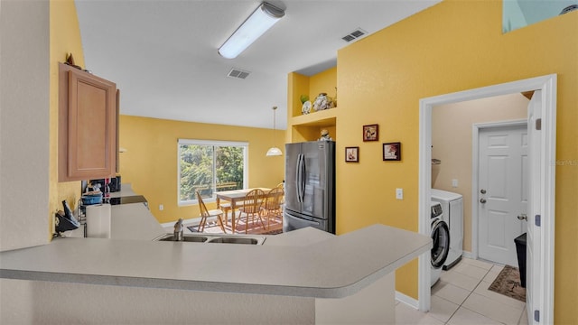 kitchen featuring sink, kitchen peninsula, stainless steel fridge, decorative light fixtures, and light tile patterned flooring